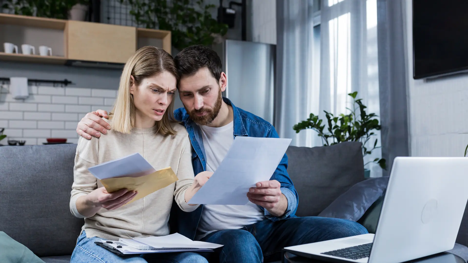 Pareja preocupada revisando documentos financieros, ilustrando el impacto de la insolvencia en las finanzas personales